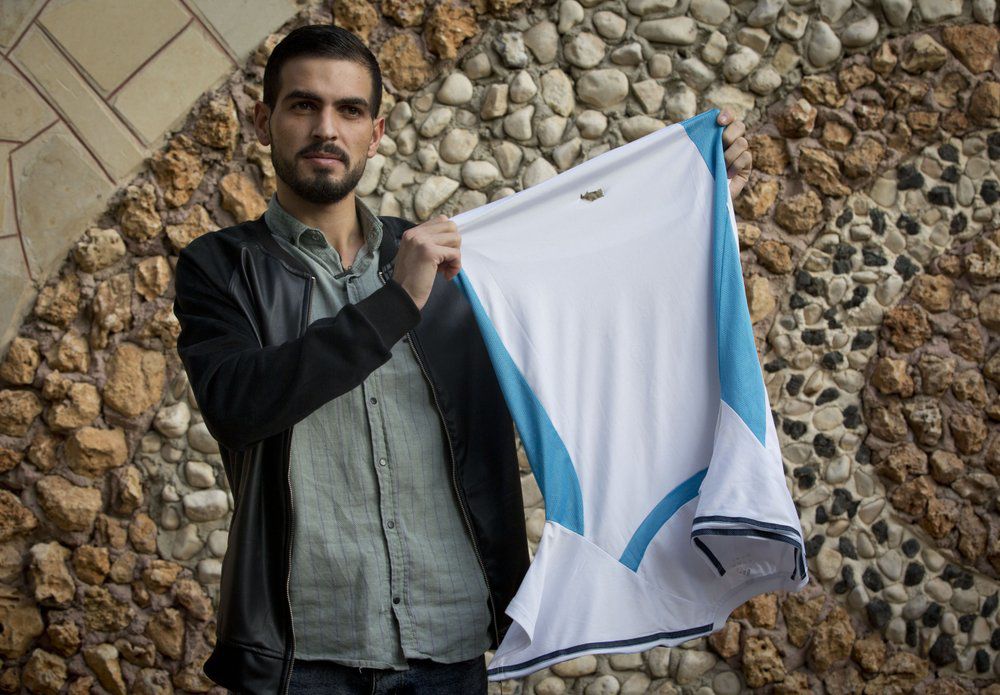 Palestinian Karam Qawasmi holds up shirt